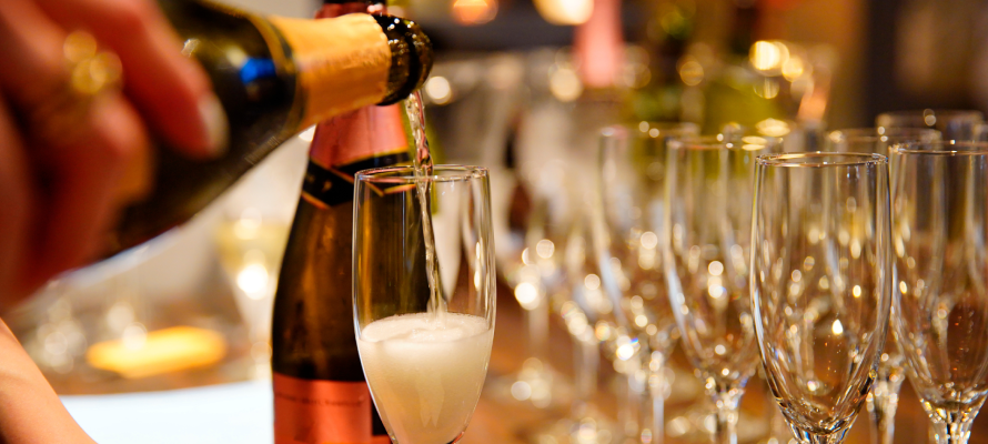 A server pours multiple glasses of sparkling wine for wedding guests
